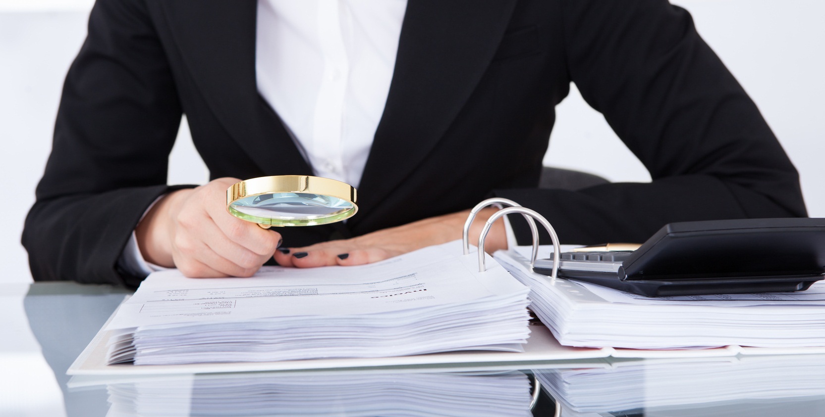 Closeup of uditor scrutinizing financial documents at desk in office